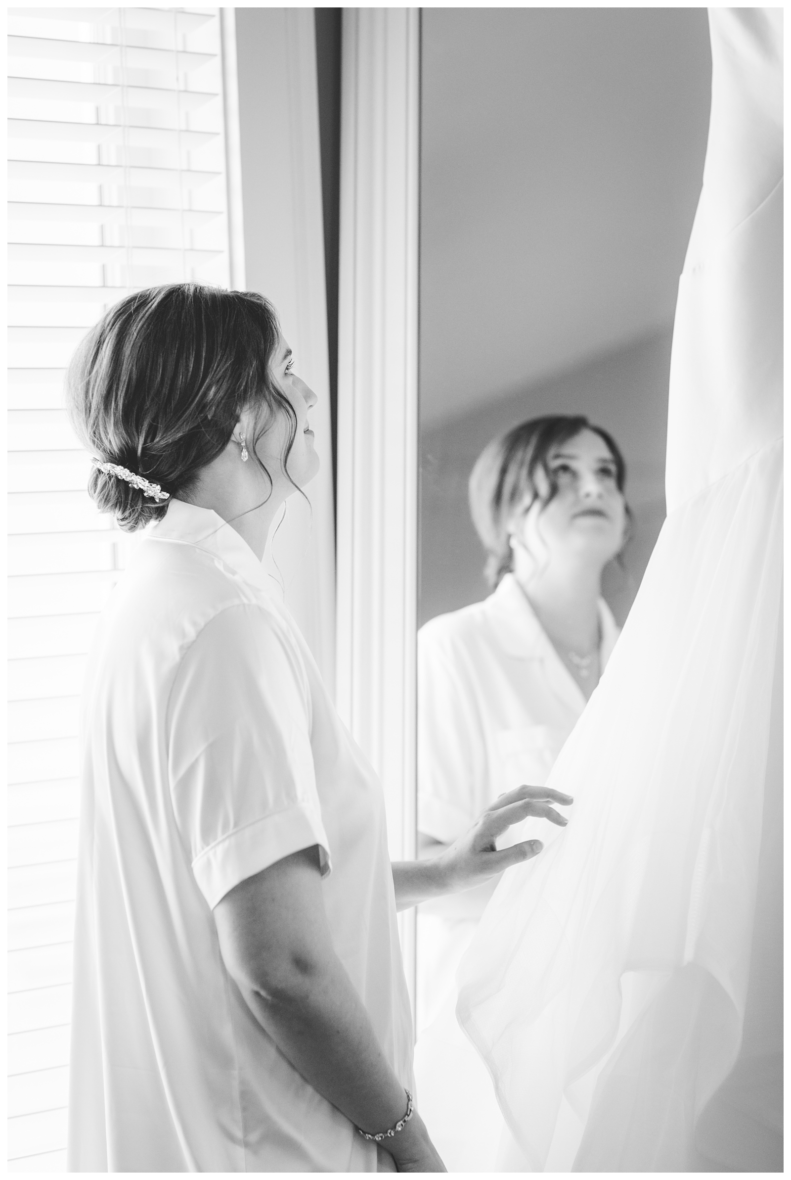 Bride looking at wedding gown hanging